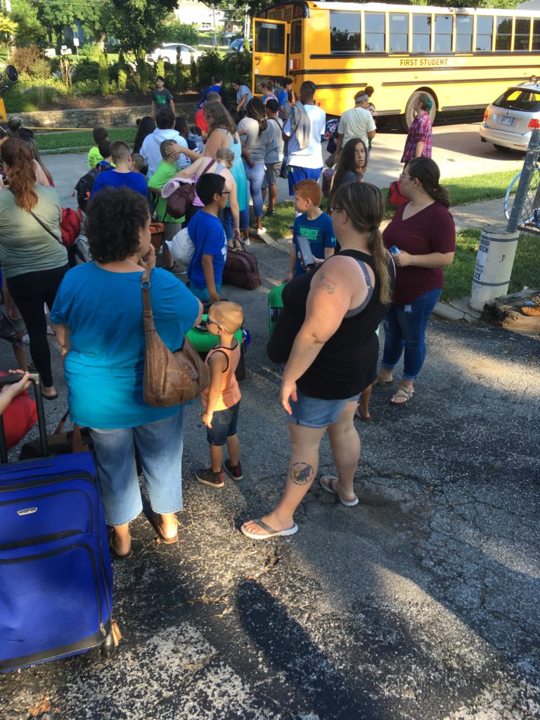 Campers getting ready to board the big yellow bus. Parents getting ready to help their camper board the bus. 