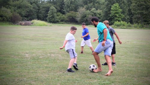 Campers and counselor playing soccer