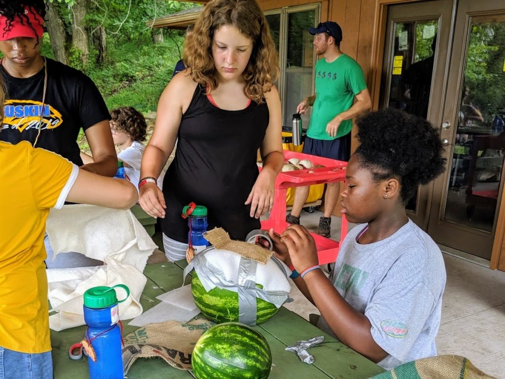 Campers building a shell for their watermelon. Volunteer counselor, David, remembers this as one of his favorite activities. 