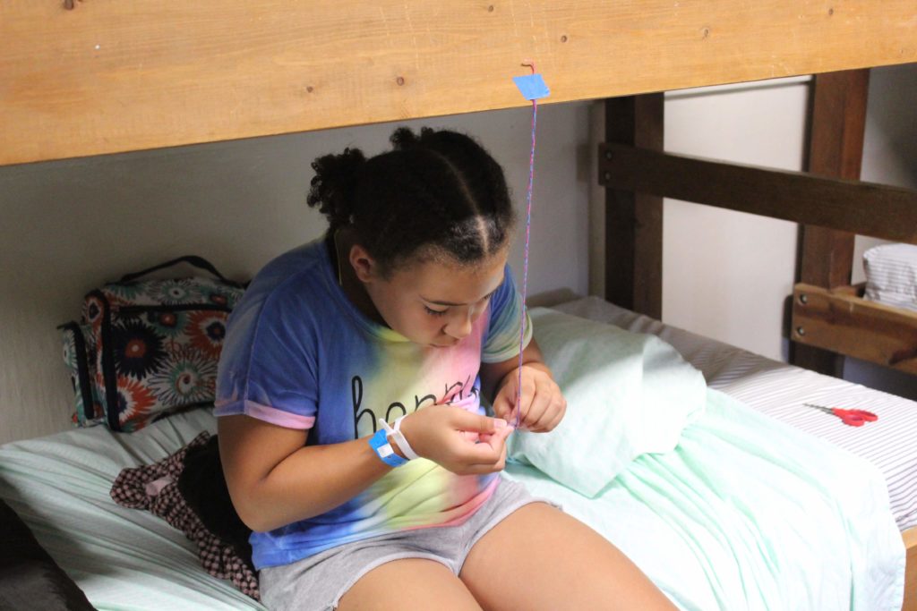 camper making a friendship bracelet during quiet time